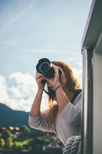 A woman uses a camera to photograph a scenic view from a boat.