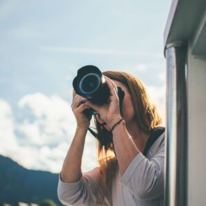 A woman uses a camera to photograph a scenic view from a boat.