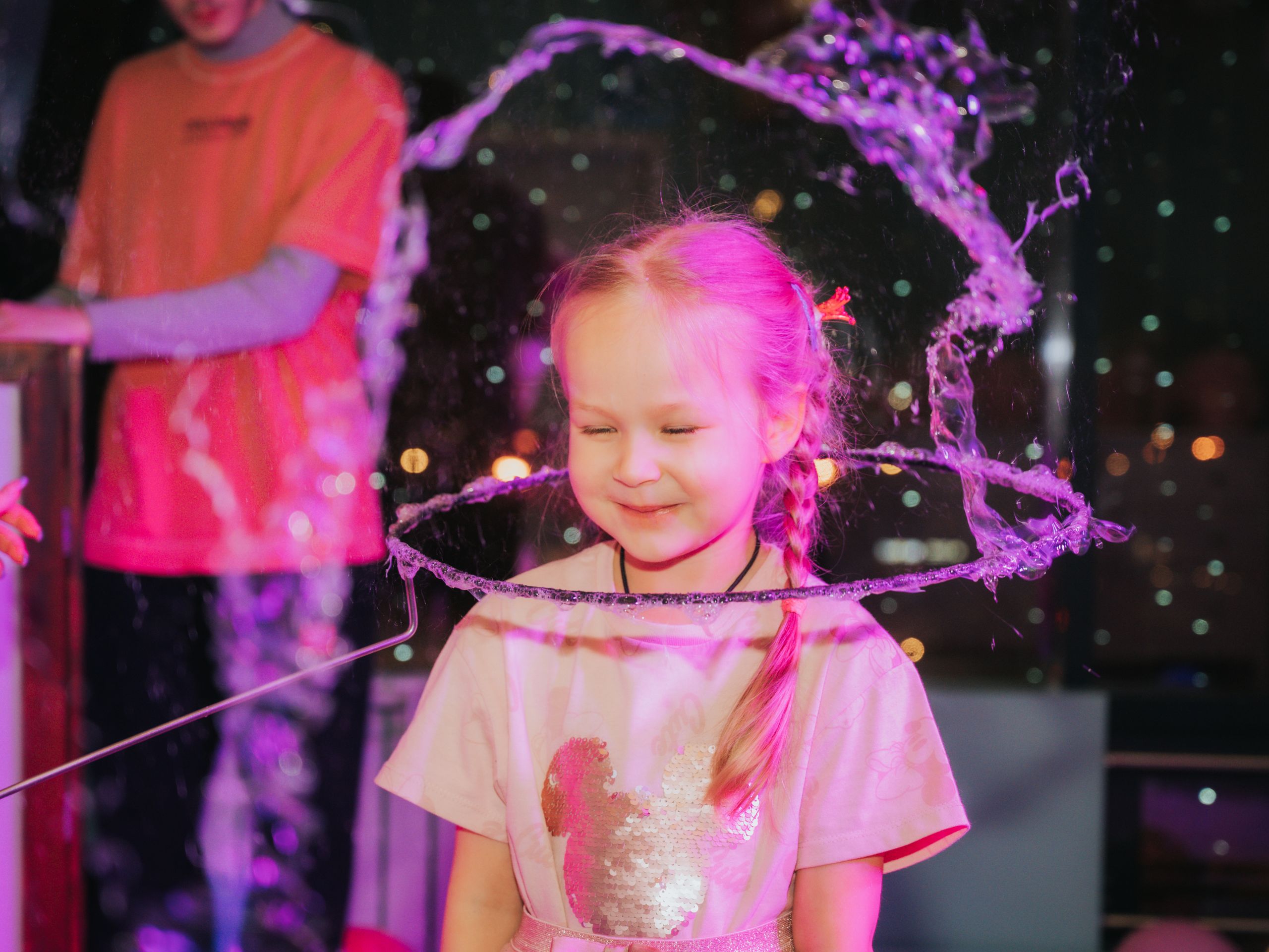 A smiling child enjoying a playful moment with bubbles at a lively indoor celebration.